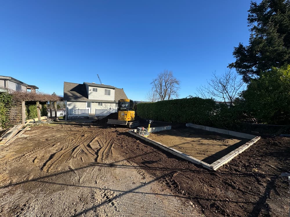 Construction site with heavy machinery preparing a foundation under clear blue skies.