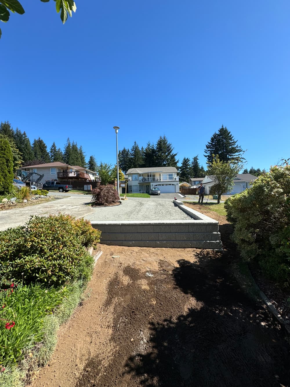 Residential neighborhood with new concrete driveway and homes under clear blue sky.