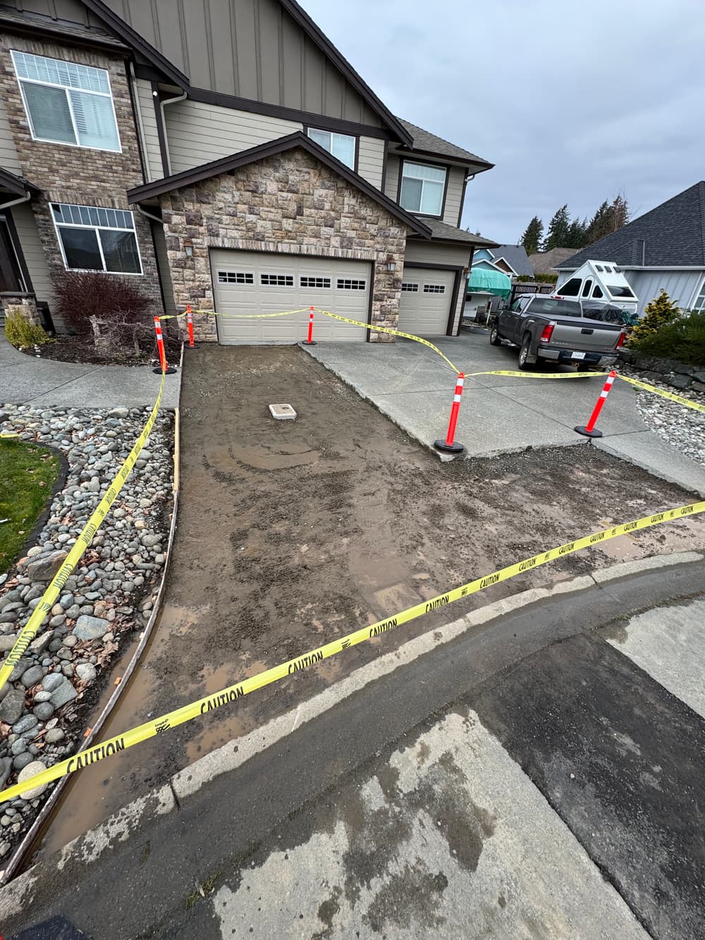 Construction site with caution tape around driveway and equipment, indicating ongoing work.